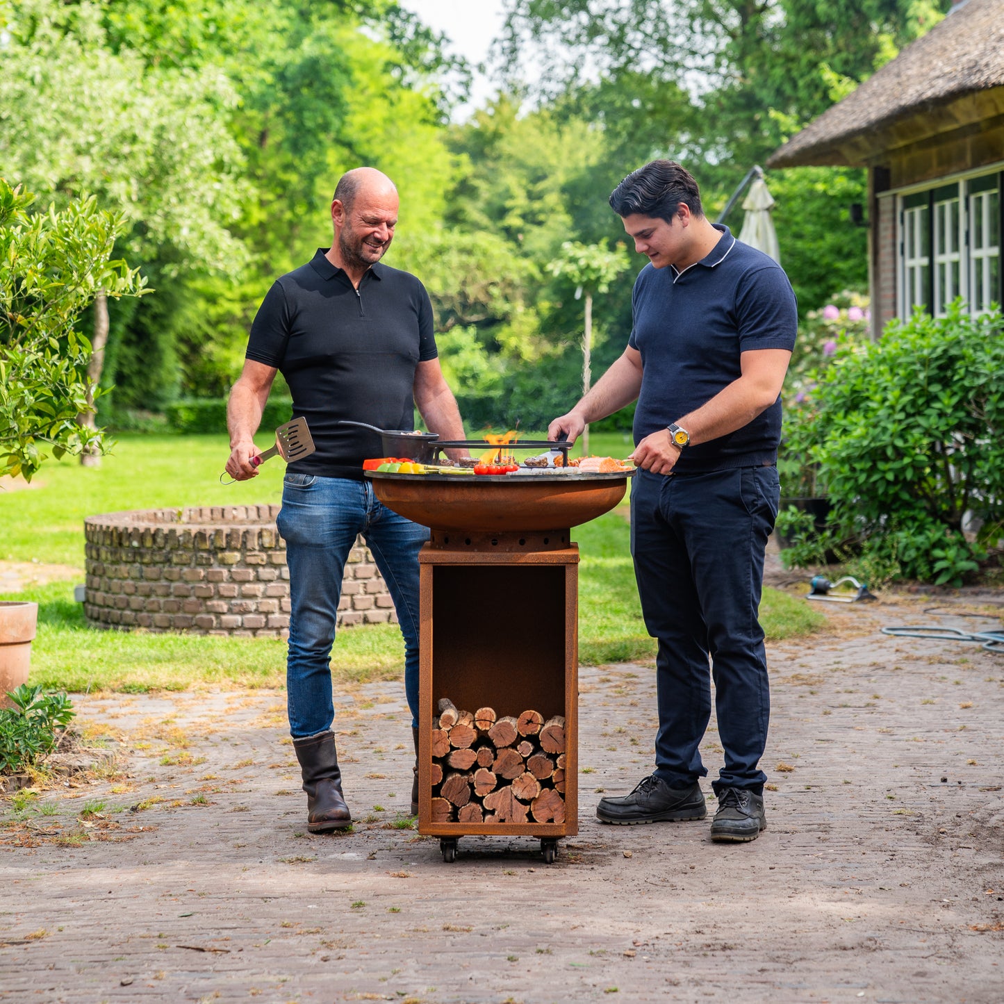 BBQ Plancha Grill Cortenstahl 8mm Camarada 2.0 - Mit Holzschürhaken und Holzlagerung Ø70cm